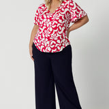 Plus sized woman wear summer ready top that is the perfect blend of comfort and style, with a delicate flutter sleeves that adds a touch of femininity and movement. The top comes in a sophisticated red base with a striking ivory floral design. Made from dry-touch jersey, this fabric offers a breathable soft feel, ideal for summer months. To ensure you stay cool and comfortable throughout the day.  Leina & Fleur stock sizes 8-24.