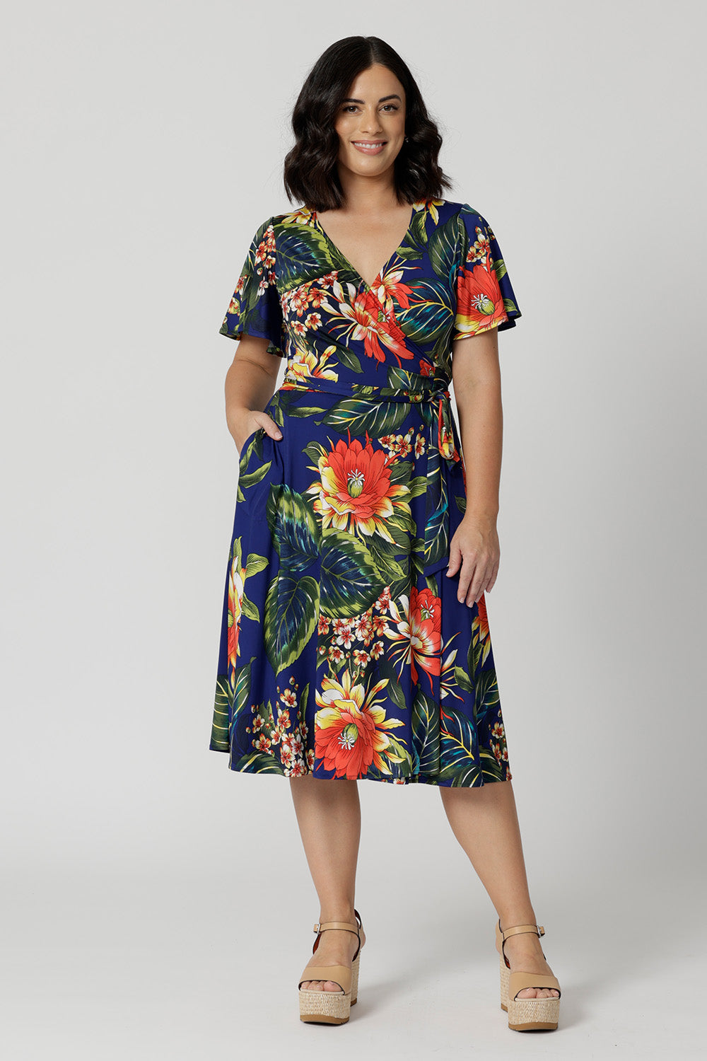 Petite model wears functioning wrap dress. Flattering silhouette suitable for various occasions such as resort wear, travel wear and spring weddings. Woman's clothing brand Leina & Fleur stock sizes from 8-24. Shop this summer ready dress in petite sizes and plus sizes.