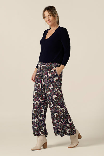 A size 10, 40 plus woman wears pull-on, wide leg pants in paisley print jersey with a long sleeve, V-neck top in Navy blue by Australian and New Zealand women's clothing brand, L&F. Comfortable trousers for the office and weekend wear, these printed pants are Australian-made in sizes 8 to 24.