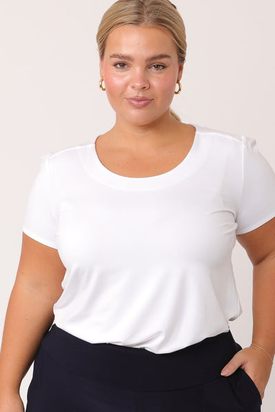 A petite woman with curve wears a round neck, short sleeve white bamboo jersey top. Great as a comfortable work top, this plus size top is a classic top with tailored details to elevate your outfits!