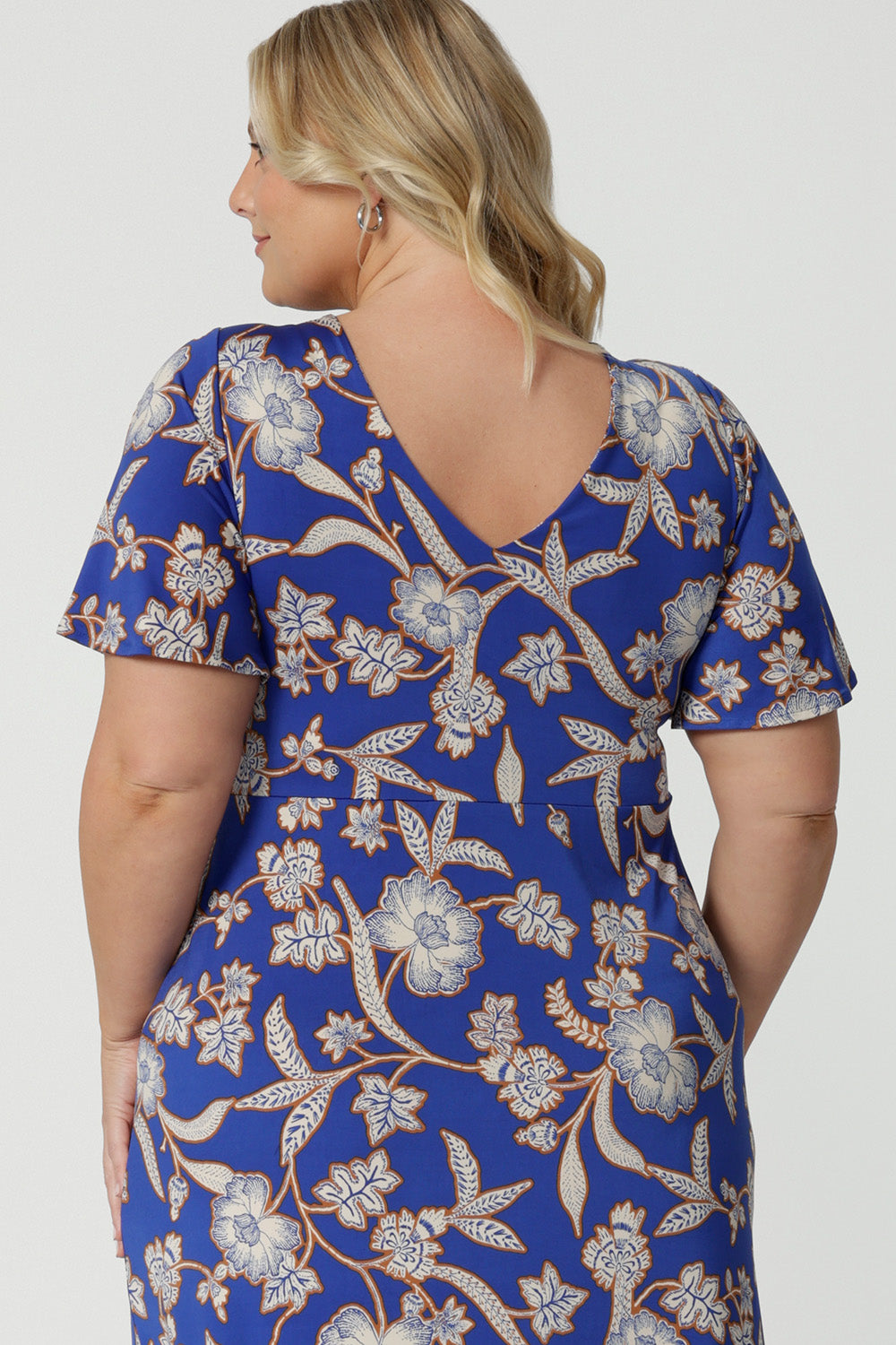 Back view of a good empire line dress for  plus size women, this twist front jersey dress in size 18 has flutter sleeves and a ruffle hem. A blue dress with floral print, be holiday ready with this travel and cruise wear dress style. Made in Australia by Australian and New Zealand women's clothes brand, Leina & Fleur, shop their petite to plus sizes dresses online.