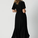 An image of the back of a curvy midsize woman over 40 is wearing a maxi wrap dress in black. Made in Australia by Australian fashion brand Leina & Fleur in sizes 8 to 24.