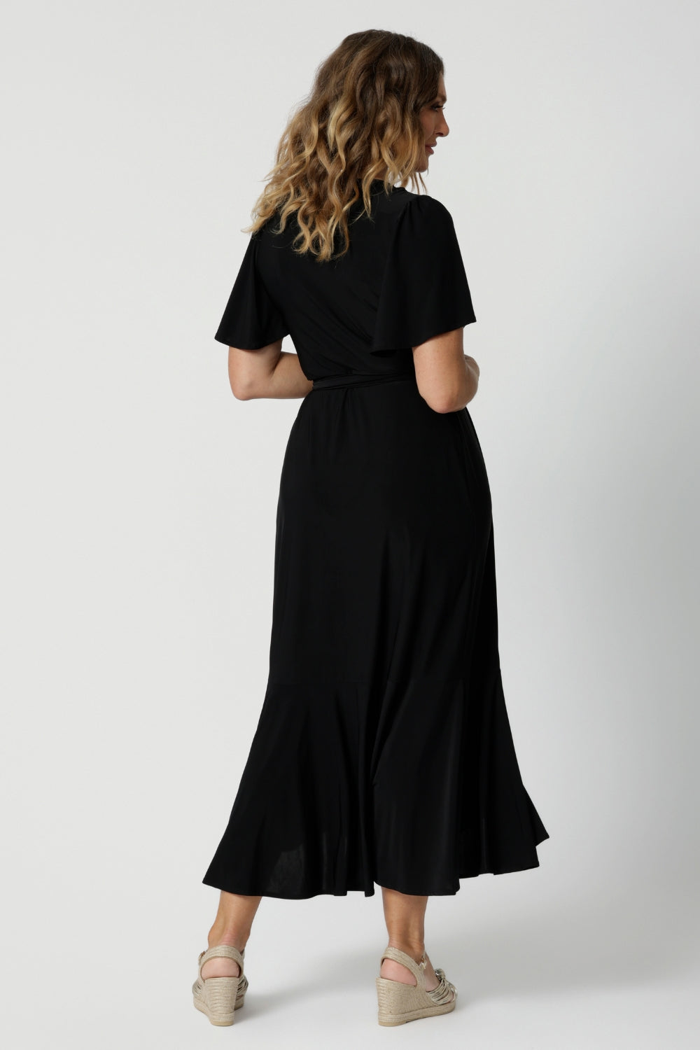 An image of the back of a curvy midsize woman over 40 is wearing a maxi wrap dress in black. Made in Australia by Australian fashion brand Leina & Fleur in sizes 8 to 24.