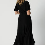 An image of the back of a curvy midsize woman over 40 is wearing a maxi wrap dress in black. Made in Australia by Australian fashion brand Leina & Fleur in sizes 8 to 24.