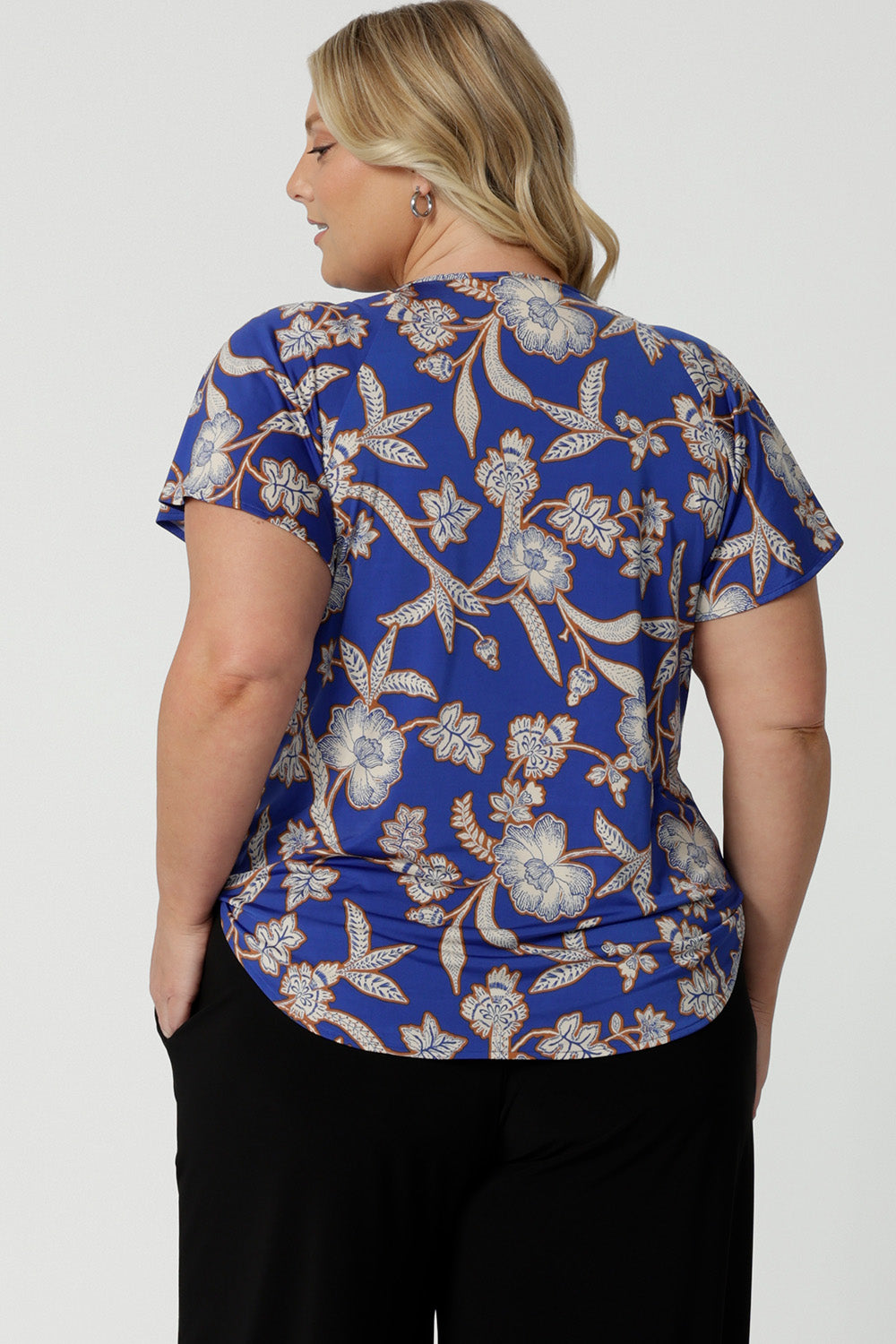 Back view of a summer top for plus size women with flutter sleeves, a curvy size 18 woman shows the relaxed fit of this jersey top. With a holiday print and in lightweight, easy care jersey, this is the perfect top for travel and cruise wear. Made in Australia by Australian and New Zealand women's clothes label, Leina & Fleur shop plus size tops online.