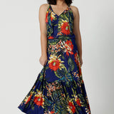 Full body image of a petite woman wears floral printed maxi dress. This travel ready dress has a halter neck and a ruffle skirting. Easy care fabric has a floral design with orange and yellow flowers on a navy base. This Australian made dress is comfortable and gives great stretch. Leina and Fleur is a women’s clothing company that actively stocks plus sizes & petite sizes ranging from 8 to 24.