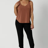 A great plus size cami top for off duty wear or event dressing. Shown on as a top for over 40s women on a size 12 woman, this cami top is worn with tapered leg travel pant in black. Eddy Cami in Clay has wide shoulder straps, a soft V-neckline and loose fitting slinky jersey body. Made in Australia by Australian fashion brand, Leina & Fleur.