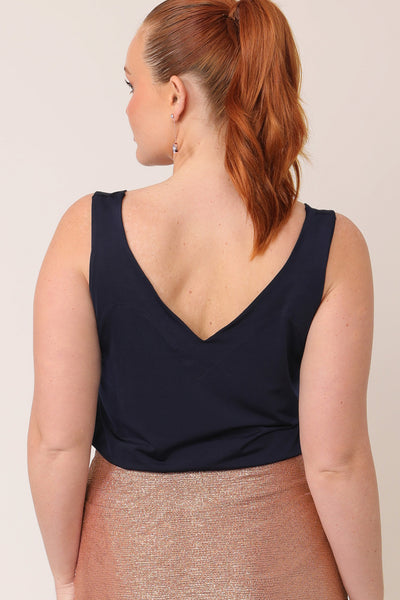 Back view of a curvy woman wearing a navy cami top with wide shoulder straps. Made in Australia by Australian and New Zealand women's occasionwear brand, L&F this slinky jersey top wears well with evening and cocktail attire skirts, pants and suit jackets.