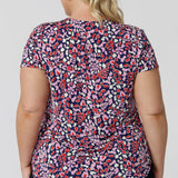 Back viewof a work  top for plus size women. This V-neck top with tailroed tuck is a comfortable top for women.  A size 18 woman wears a a plus size short sleeve V-neck jersey top in red, pink, white and navy print. Made in Australia top by Australian and New Zealand women's clothes brand, Leina & Fleur, shop their petite to plus size tops online. 