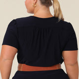 Back view of a petite woman with curve wears a navy blue V-neck top with short sleeves. A good work top for plus size women, this tailored top is made in Australia by Australian fashion brand, Leina & Fleur in sizes 8 to 24.