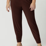 Close up of goof off duty pants for petite women. These tapered leg pants by Australian and New Zealand women's  clothes brand, Leina & Fleur are comfortable, stretchy pants in espresso brown jersey fabric. Shop pants for petite height women online in sizes 8 to 24.