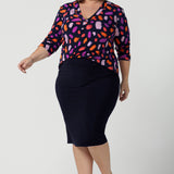 Size 18 curvy woman wears the Jaime top in Palette. A brush stroke inspired abstract print on a navy base with fuchsia, red, orange and pink spots. A v-neck pleat front top great for work to weekend. Comfortable jersey and easy care. Made in Australia for women size 8 - 24.