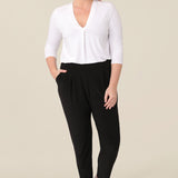 A great top for curvy women, this white bamboo jersey top is tailored with a pleat below the V-neck. Lightweight and breathable, this 3/4 sleeve top makes a comfortable work top, looking classic under workwear jackets and suits. A classic top worn with dropped crotch, cropped black travel pants, this white jersey top is good for casual wear and travel capsule wardrobes too. Shown on a curvy, mid size woman, this top is also available in petite and plus sizes online at women's clothing brand, Leina & Fleur. 