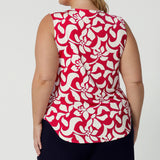 Back view of plus sized woman wears sleeveless ivory coloured summer top with shades of vibrant red. Made from easy care dry-touch jersey for easy wearing and easy packing on your travels.