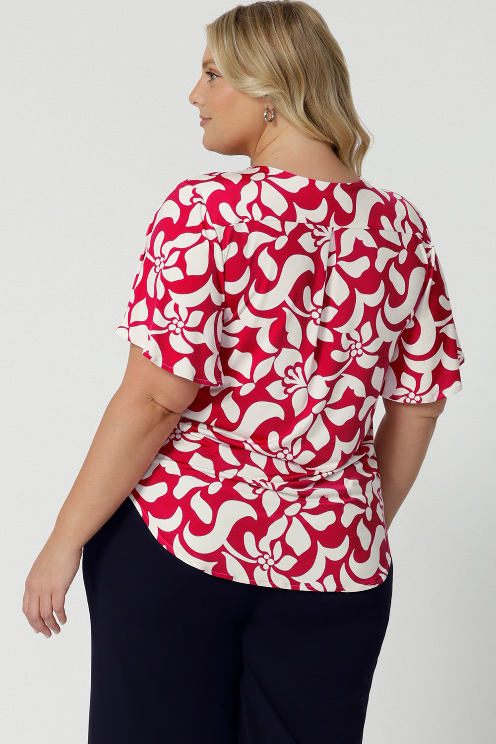 Back view of plus sized model wearing Lila Top in Cherry Charm. A flutter sleeve top with a short tail hem line, made of dry touch jersey fabric that is cooling and comfortable. Womens clothing brand Leina & Fleur  from 8-24 proudly stocks sizes 8-24.