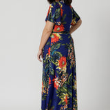 Back view image of petite sized model wearing floral wrap dress. Easy care top is made of slinky jersey that is crease-resistant perfect for travel. Comfortable floral dress is flattering and relaxed for all-day travel wear. Leina & Fleur stock sizes 8-24. 