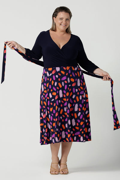 Size 18 curvy woman wears the Nerida dress. Functioning fit and flare wrap dress with a navy bodice and printed skirt. 3/4 Sleeves and functioning pockets. Made in Australia for women. Size 8 - 24. Styled back with a brown sling back heel.