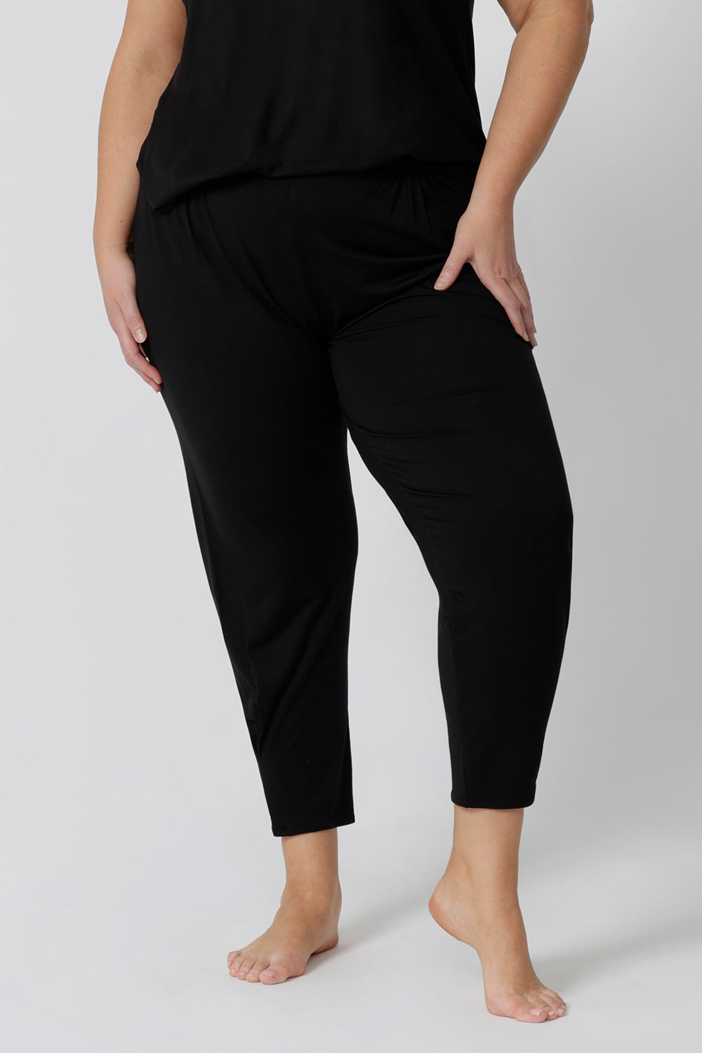 Close up of a good loungewear pant for curvy women. These black tapered, plus size pants are pull-on pyjama pants. Worn with black bamboo cami top, this is a breathable, thermo-regulating pyjama set and makes get sleepwear for night sweats and hot flushes. Shop loungewear sets online at L&F Australia.