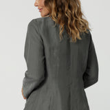 Back view image of 40 year old woman wears cool toned blazer. Light weight and breathable designs helps stay cool  while travelling or during warmer weather. Linen blend blazer is stocked in sizes 8-24 online at Leina & Fleur. 