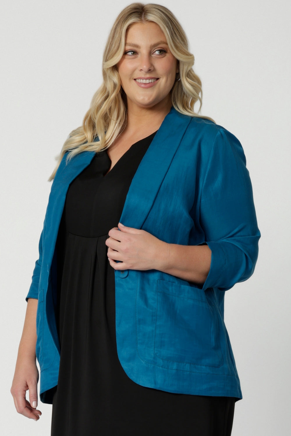 Vibrant teal blazer pictured on plus sized woman is perfect for summer travel. Made with linen, tencel and cupro fabric this blazer is light weight and breathable. Clothing brand Leina & Fluer stock sizes in this travel read blazer in 8-24.