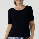 A beautiful and comfortable workwear top for plus size, curvy women, this short sleeve, boat neck top in navy blue is shown on a size 8. A quality top for workwear, this slim fit jersey top is made in Australia by women's clothing brand, Leina & Fleur.