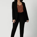 Leina & Fleur's petite sized model wearing black workwear blazer. Designed for modern professionals who value functionality and comfort. Woman's fashion brand Leina & Fleur stock soft suiting in sizes 8 to 24. Find this easy care work blazer and matching suit pants in plus size and petite sizes.