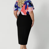 Back view of a plus size straight-cut black midi skirt, is crafted in lightweight scuba crepe jersey for curvy women. Made in Australia by the Australian and New Zealand women's clothes brand, this easy-care, stretchy skirt delivers comfort and style for plus size women - available in skirt sizes 8 to 24.