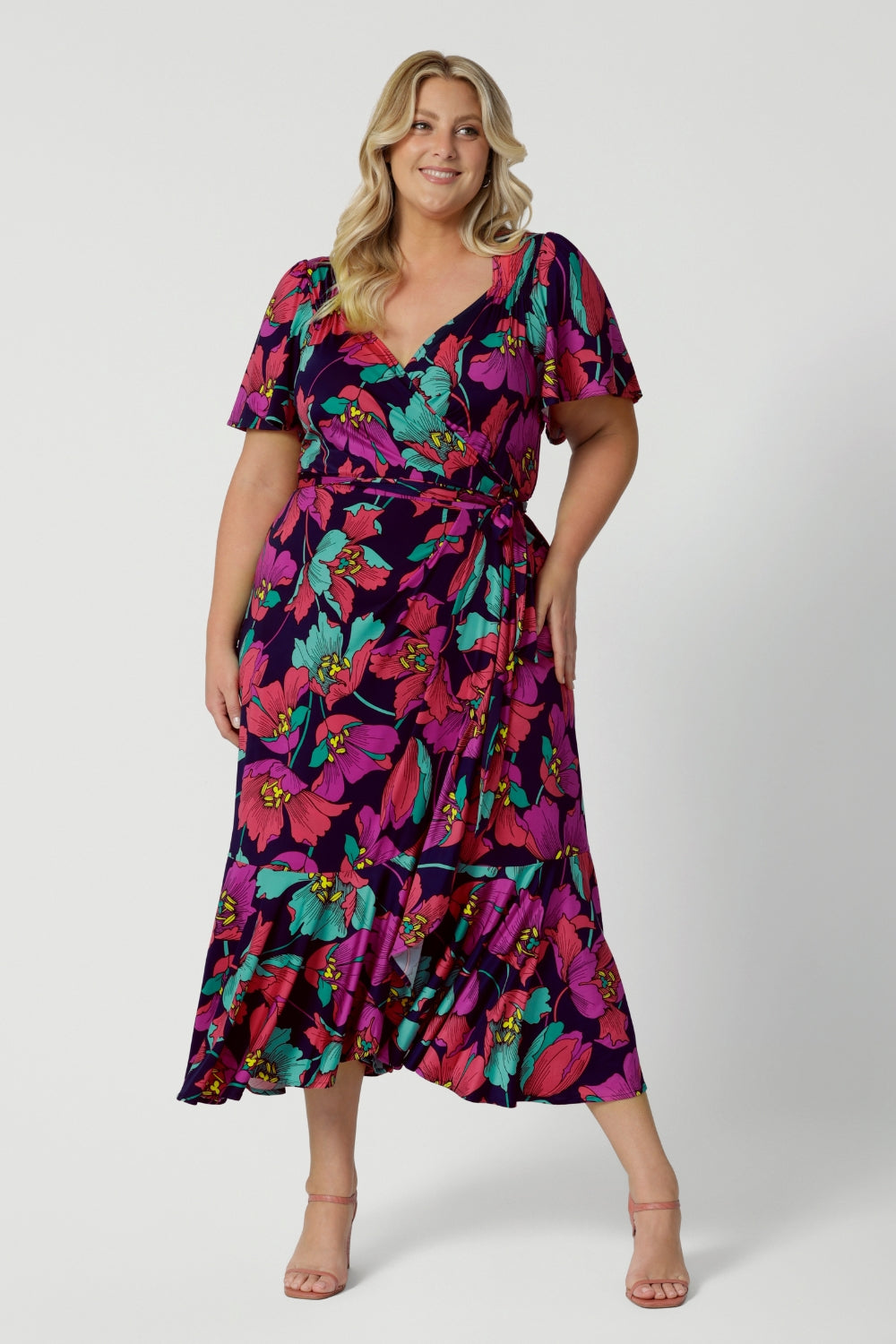 A size 18 woman over 35 wears a maxi wrap dress in a bold print. An elegant wrap dress with a tiered ruffle skirt,  sweetheart neckline and flutter sleeve. Made in Australia for women size 8 - 24 by Leina & Fleur.