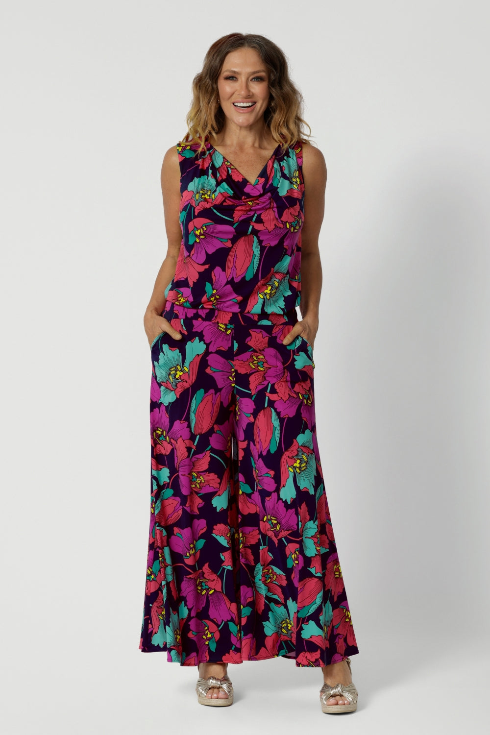 A curvy size 10 woman over 40 wears the Caspian Palazzo pant in a bright floral print. In soft and lightweight jersey this pant features side pockets and a flared leg opening. Made in sizes 8 to 24 by Australian fashion brand Leina & Fleur.