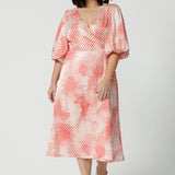 Showing a good dress for petite women, this silky wrap dress has an orange spot print and 3/4 lantern-shaped sleeves. Made in Australia by women's clothing brand, Leina & Fleur, wear this 3/4 sleeve wrap dress for wedding guest outfit and summer event  wear. Shop this summer wedding guest and event wear outfit online in sizes 8 to 24.