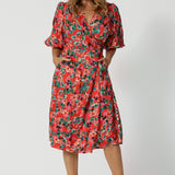 Showing a good dress for over 40s women, this silky wrap dress has a floral print on orange base, and 3/4 lantern-shaped sleeves. Made in Australia by women's clothing brand, Leina & Fleur, wear this 3/4 sleeve wrap dress for wedding guest outfit and summer event  wear. Shop this summer wedding guest and event wear outfit online in sizes 8 to 24.