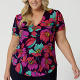 A curvy size 18 woman over 35 wears a top with a v-neckline and short sleeves. It has a bold floral print. The top is handmade in Australia by Australian fashion brand Leina & Fleur in sizes 8 to 24. 