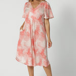 Showing a good dress for over 40s women, this silky flutter sleeve dress in viscose fabric has an orange spot print. Made in Australia by women's clothes label, Leina & Fleur, this lightweight summer dress is breathable. Shop this summer wedding guest and event wear outfit online in sizes 8 to 24.