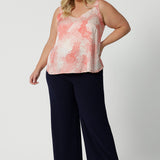 Showing cami top for plus size women. This silky cami top with wide shoulder straps and orange spot print is worn with navy blue wide leg pants.  Made in Australia by women's clothing brand, Leina & Fleur, wear this lightweight cami top is breathable top for summer wear. Shop this summer top for women  online in sizes 8 to 24.