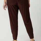 Back view of good off duty trousers for petite women. These tapered leg pants by Australian and New Zealand women's clothes brand, Leina & Fleur are comfortable stretchy pants in espresso brown jersey fabric. Shop pants for petite height women online in sizes 8 to 24.