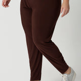 Close up of off duty pants for tall, plus size women, these tapered leg, long length pants by Australian and New Zealand women's  clothing brand, Leina & Fleur are comfortable stretchy pants in espresso brown jersey fabric. Shop travel pants for plus size women and ladies tall pants online in sizes 8 to 24.