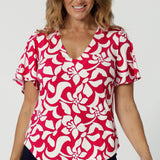 Front image close up of over 40 year old model wearing red flutter sleeve top with ivory floral details. High quality fabric used to make this top is dry touch jersey. Australian made for woman in Australia & New Zealand. Sizes stocked range from 8 - 24 with plus and petite friendly sizes included. 