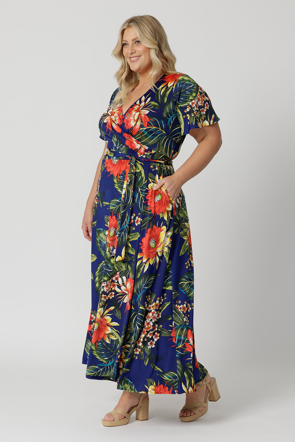 Wrap dress worn by plus sized model has a floral design. Cruise and resort style ready dress is made of slinky jersey. Made in Australia for womans clothing brand Leina and Fleur. Shop wrap dresses online in sizes 8 to 24.