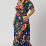 Wrap dress worn by plus sized model has a floral design. Cruise and resort style ready dress is made of slinky jersey. Made in Australia for womans clothing brand Leina and Fleur. Shop wrap dresses online in sizes 8 to 24.