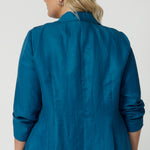 Image showcases teal blazer from the back featuring Australian made tailoring. While the relaxed fit offers versatility for any occasion it is perfect for travel. Provides a light weight style for your journeys. Shop this linen blazer in sizes 8-24.