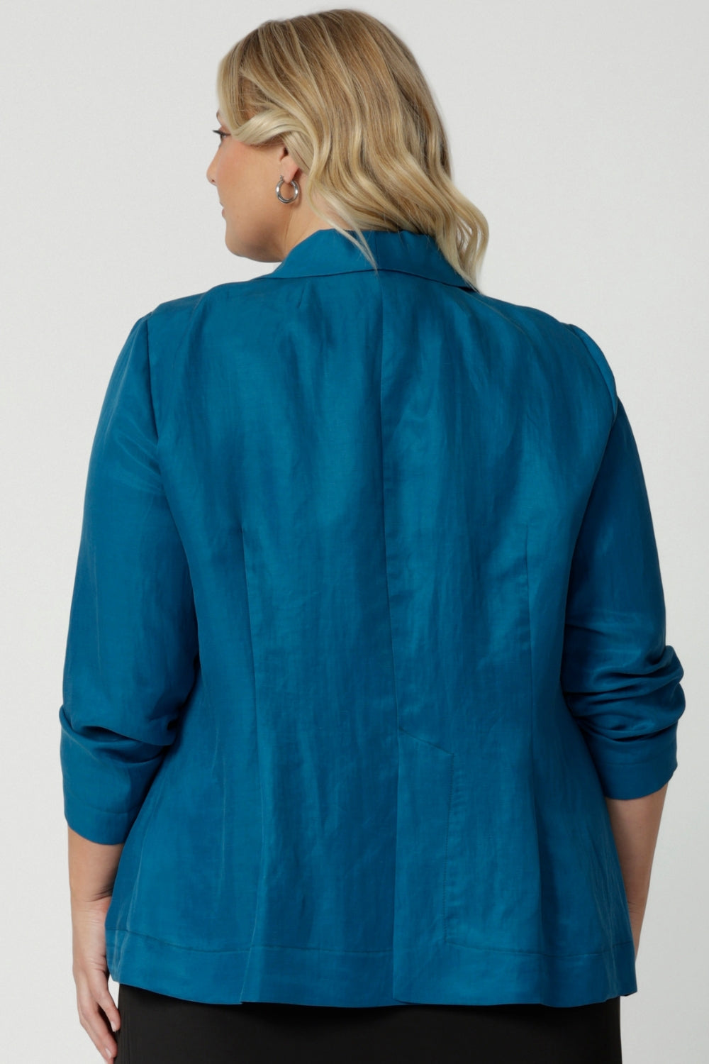 Image showcases teal blazer from the back featuring Australian made tailoring. While the relaxed fit offers versatility for any occasion it is perfect for travel. Provides a light weight style for your journeys. Shop this linen blazer in sizes 8-24.