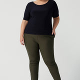 A good top for plus size, curvy women, this short sleeve, boat neck top in navy blue is worn with slim leg tailored pants in olive green ponte fabric. Shown on a size 18 woman, this is a quality top for workwear. Shop slim fit jersey tops made in Australia by women's clothing brand, Leina & Fleur in their online store now!