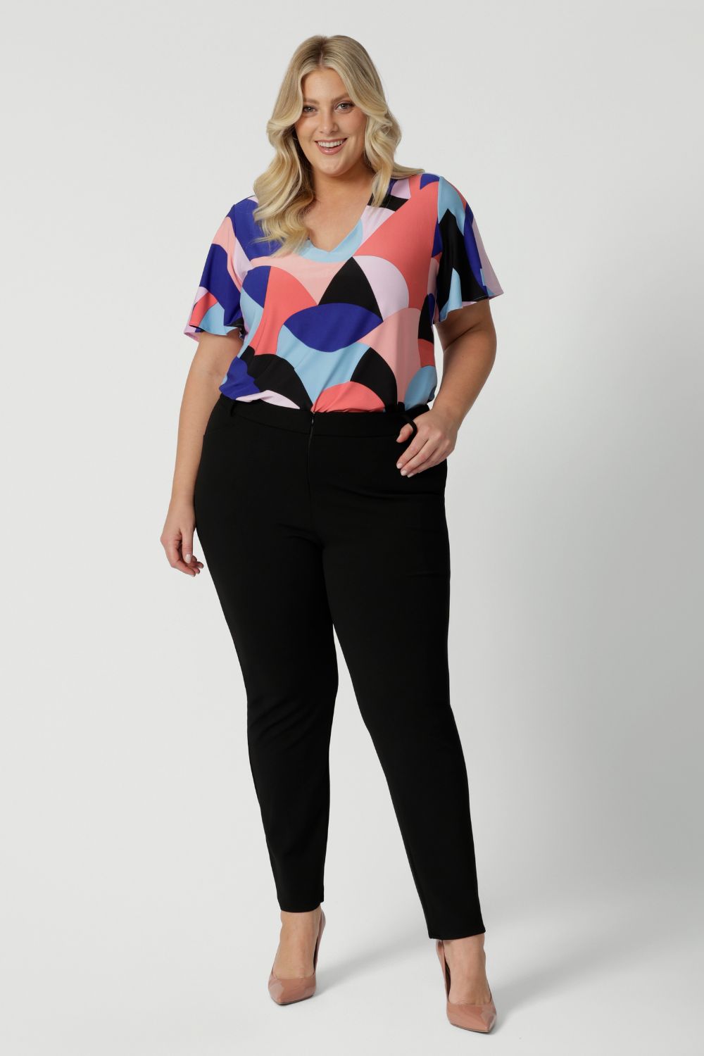 Image of plus sized woman wearing black work wear pants. The Corbin Pant is made of stretchy black Scuba Crepe fabric. This off duty pant style is breathable and has a matching black blazer to complete the full suit look.  Made in Australia by Leina & Fleur, a woman's clothing brand that stocks sizes 8-24.