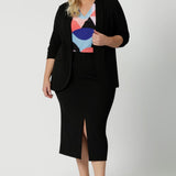 Leina & Fleur's plus sized model wearing black workwear blazer. Manufactured for modern professionals who values style, functionality and comfort. Womans clothing brand Leina & Fleur stock soft suiting in sizes 8 to 24. Find this easy care work blazer and matching suit pants in plus size and petite sizes.