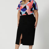 Leina & Fleur's plus size straight-cut black midi skirt, is crafted in lightweight scuba crepe jersey for curvy women. With a front split, this skirt with pockets is worn with a flutter sleeve women's top in coral and cobalt print. Made in Australia by the Australian and New Zealand women's clothing brand, this easy-care, stretchy skirt delivers comfort and style for plus size women - available in skirt sizes 8 to 24.