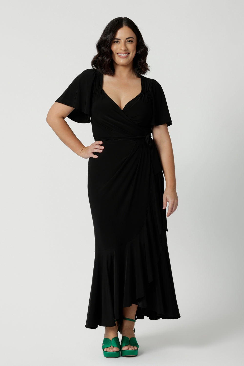 A petite-height woman is wearing a maxi wrap dress in black as a black tie event outfit. Made in Australia by Australian fashion brand Leina & Fleur in sizes 8 to 24.