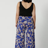 Wide leg pants for summer don't come much better than this! Worn by a size 10, woman, this is a back view of petite friendly wide leg pants in easy care jersey with a blue, caramel and white floral print. Worn with a black cami top, these wide leg culottes are made in Australia by Australian and New Zealand womens clothing brand, Leina and Fleur. Shop wide leg pants in petite to plus sizes.