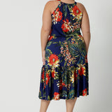 Back view image of plus sized model wears midi floral dress. Dress for summer has a halter neck detail and ruffle hem. Floral fabric use is easy-care and crease-resistant perfect for travel. Leina & Fleur is a womans clothing brand that actively stocks sizes from 8-24. Shop this summer ready dress in petite sizes and plus sizes.