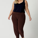 Good travel pants for curvy, plus size women. These tapered leg pants by Australian and New Zealand women's  clothing brand, Leina & Fleur are comfortable stretchy pants in espresso brown jersey fabric. Shop travel pants for plus size women online in sizes 8 to 24.