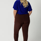 Back view of off duty pants for tall, plus size women, these tapered leg, long length pants by Australian and New Zealand ladies clothing brand, Leina & Fleur are comfortable stretchy pants in espresso brown jersey fabric. Shop travel pants for plus size women and ladies tall pants online in sizes 8 to 24.